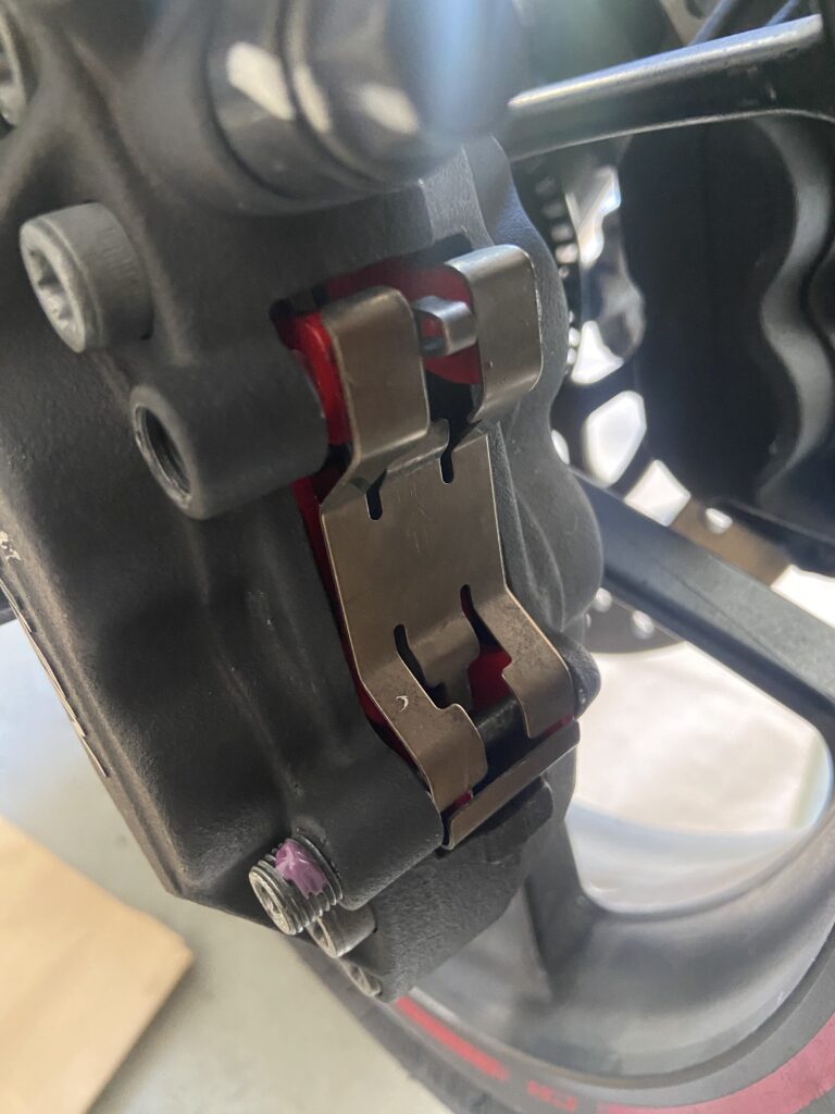 Photo of a caliper with new brake pads being installed