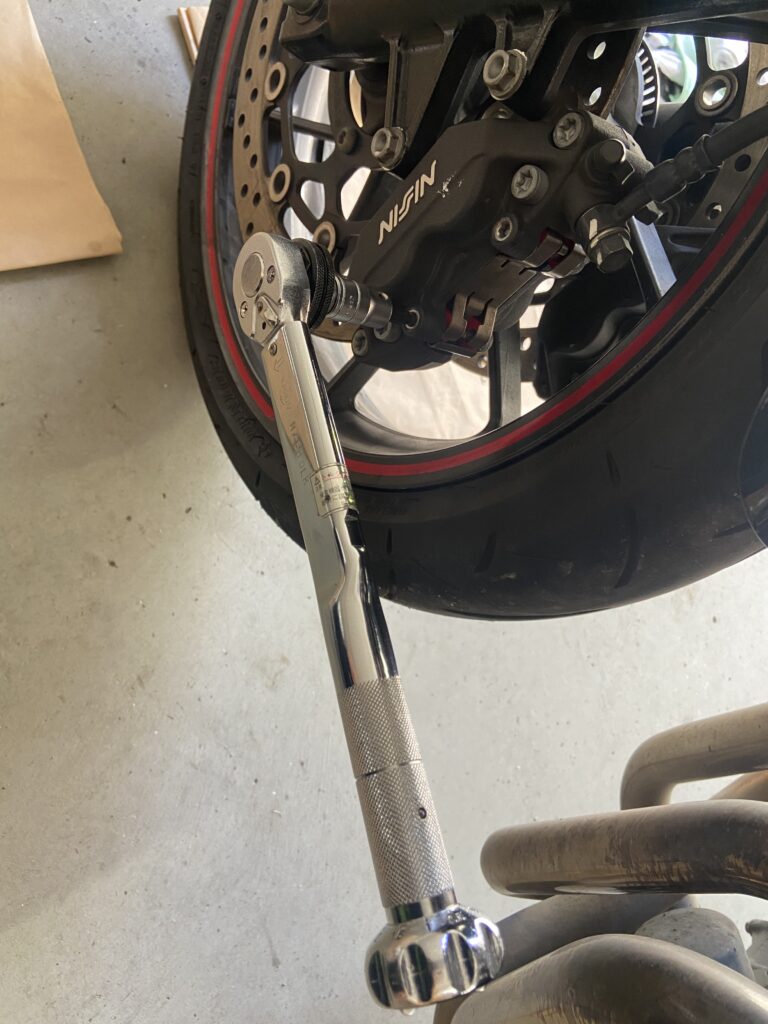 Image showing a torque wrench being used to tighten a brake caliper bolt